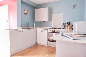 eine Küche mit weißen Schränken und einer Arbeitsplatte in der Unterkunft Kingfisher Cottage in Youlgreave