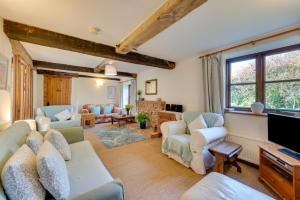 a living room with a couch and chairs and a tv at Leath Barn Cottage in Somerton