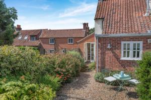 einen Garten vor einem Backsteinhaus in der Unterkunft Baytree Cottage in Melton Constable