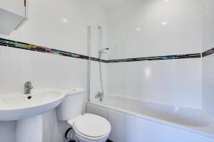 a white bathroom with a toilet and a sink at Two Buoys in Sheringham +3 photos