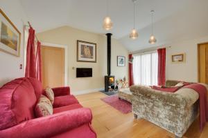 a living room with two red couches and a fireplace at Woodland Lodge in Wilby +7 photos