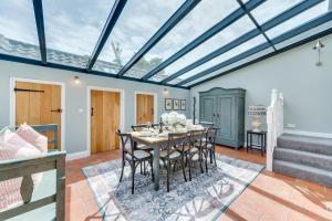 a conservatory with a dining room with a table and chairs at Sand Stone Cottage in Northrepps