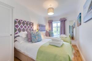 a bedroom with two beds with green and blue pillows at Sand Stone Cottage in Northrepps