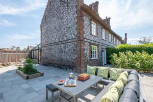 a patio with a couch and a table in front of a brick building at Sand Stone Cottage in Northrepps