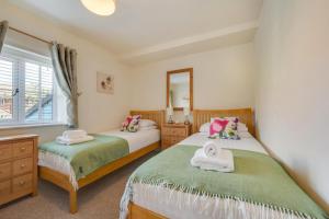 ein Schlafzimmer mit zwei Betten und einem Spiegel in der Unterkunft Fishermen's Cottage in Sheringham