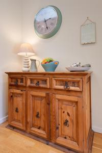 einem Holzschrank mit einer Uhr an der Wand in der Unterkunft Fishermen's Cottage in Sheringham
