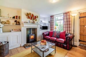 a living room with a red couch and a fireplace at Vine Cottage in Walberswick