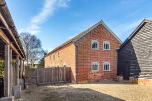 a red brick building with a wooden fence at East Barn Cottage in Aldringham