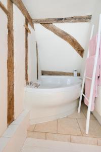 a white bath tub in a bathroom with wooden ceilings at London Cottage in Halesworth