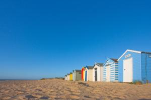 a row of beach houses on a sandy beach at London Cottage in Halesworth