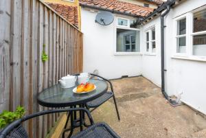 a table with a plate of fruit on a patio at London Cottage in Halesworth +4 photos