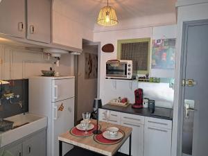 a small kitchen with a table and a white refrigerator at Très joli studio au calme dans le cœur du village in Prats-de-Mollo-la-Preste