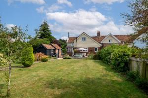 a large yard with a house and a fence at Alde Cottage in Friston