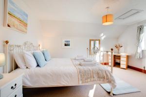 ein weißes Schlafzimmer mit einem Bett und einem Schreibtisch in der Unterkunft Haven Cottage in South Walsham