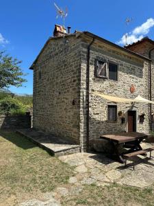 un edificio de piedra con una mesa de picnic delante de él en Poggi di Belvedere, en Pieve Santo Stefano