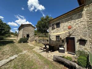 un edificio de piedra con una mesa de picnic delante de él en Poggi di Belvedere, en Pieve Santo Stefano