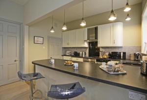 a large kitchen with a counter and chairs in it at Wing Cottage in Orford