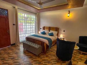 a bedroom with a bed and a chair and a window at Home Villa Eco Boutique in Arusha