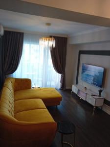 un soggiorno con divano giallo e TV di Exquisite Prima a Oradea