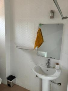 a white bathroom with a sink and a mirror at Residence Cloé in Ouagadougou