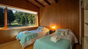 two beds in a room with a window at Stunning 4-Bedroom House Large Garden and Pool H61 by Apartments Bariloche in San Carlos de Bariloche
