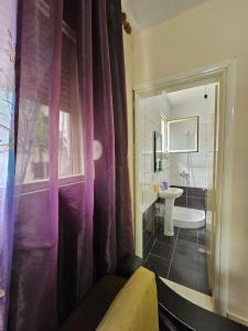 a bathroom with a purple shower curtain and a sink at Saranda Garden Rooms in Sarandë