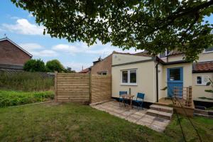 Japonica Cottage في Wenhaston: حديقة خلفية مع سور وطاولة وكراسي +3 صور