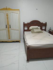 a bedroom with a wooden bed and a cabinet at Quarto para COP 30 in Belém