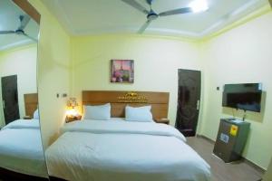 a bedroom with two beds and a flat screen tv at Nyaji Star Hotel, Tamale in Trofwi