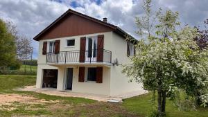 a white house with a brown roof and a tree at La Parenthèse in Longchaumois