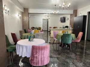 a restaurant with tables and chairs with pink and green chairs at CASA VELDONI in Brăneşti