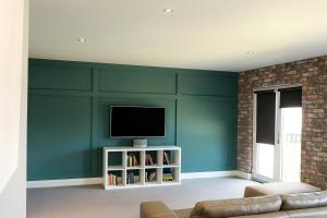 a living room with green walls and a television at Spacious Apartment NEC BHX in Solihull