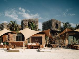 a resort with a building with umbrellas on the beach at Nômade Temple Holbox in Holbox Island