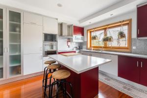 Una cocina con gabinetes y taburetes blancos y rojos. en Family retreat in Gaia, en Vila Nova de Gaia