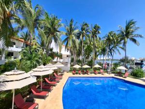 ein Resort-Pool mit Liegestühlen, Sonnenschirmen und Palmen in der Unterkunft Sina Suites Cancun - Adults Only in Cancún