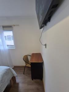 a bedroom with a table and a tv on a wall at hostal perez de arce in Punta Arenas