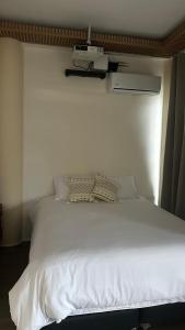 a white bed in a bedroom with a white wall at Hotel oasis Sevilla Valle in Sevilla