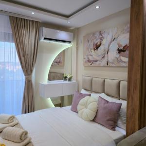 - une chambre avec un lit blanc et des oreillers violets dans l'établissement Apartman NIKOLINA, à Vrnjačka Banja