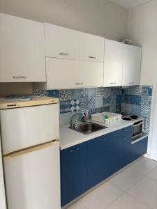 a kitchen with blue and white cabinets and a sink at Victoria's Blue studios in Siviri
