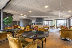 a restaurant with tables and chairs and a counter at Leonardo Hotel Lelystad City Center in Lelystad