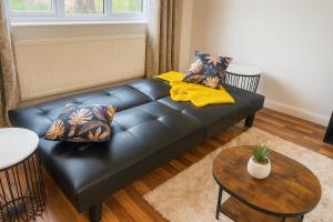 a black leather couch in a living room with a table at Modern 3-Bedroom Home with Free Parking for Family, Contractors and Tourists! in Sittingbourne