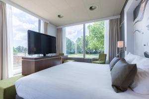 a hotel room with a large bed and a television at Leonardo Hotel Papendrecht in Papendrecht