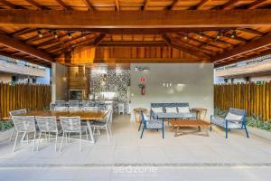 a patio with chairs and tables and a wooden ceiling at Apto 2 Suítes em Condo. c/ Piscina EKO0008 in Itacimirim