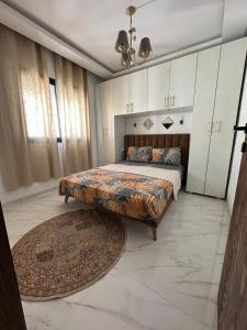 Un dormitorio con una cama grande con una alfombra grande en Cozy hotel-style emerald apartment, en El Aouina Station