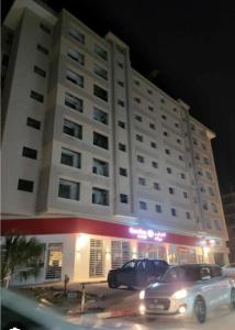 Un gran edificio blanco con coches aparcados delante. en Cozy hotel-style emerald apartment, en El Aouina Station