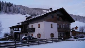 a house in the snow with a car parked in front at Enzian in Sesto