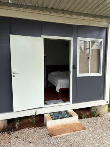 a gray house with a door and a bedroom at Cabinas Nena in Esparza