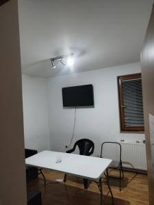 a white room with a table and a tv on a wall at Exotic Nature Hostel in Sarajevo