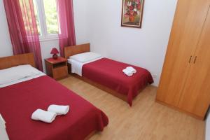 um quarto com duas camas com lençóis vermelhos e toalhas brancas em Apartments Kala em Sveti Filip i Jakov