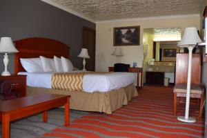 a hotel room with a bed and a desk at Travelodge Inn & Suites by Wyndham Norman in Norman